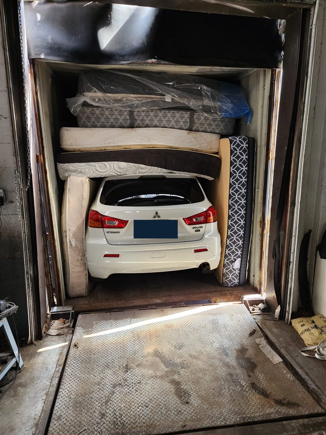 Mitsubishi RVR calé et protégé dans un conteneur en direction de Conakry, plaque masquée pour la confidentialité