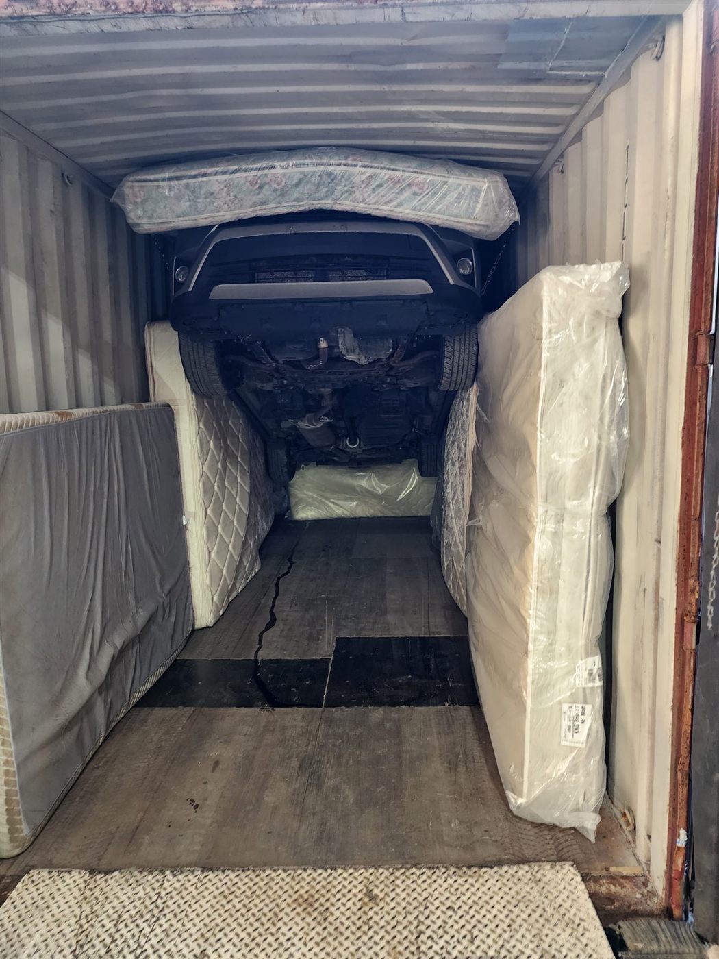 Vue intérieure d'un conteneur chargé : véhicule surélevé et marchandises calées pour le transport maritime vers la Guinée